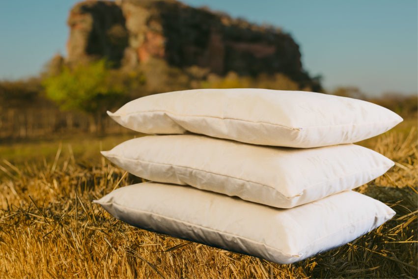 Three wool pillows stacked outdoors in a golden field