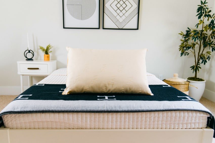 Wool pillow on a styled bed with dark throw blanket and wall art