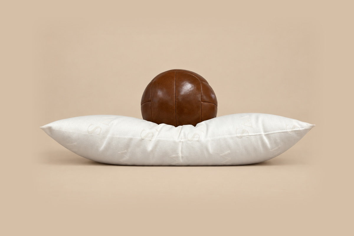 Medium wool pillow with a leather ball resting on it