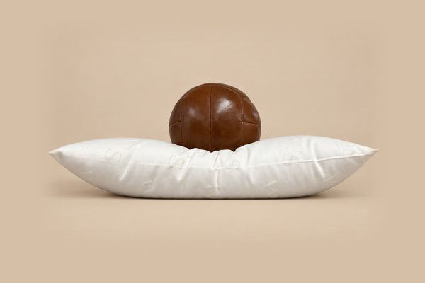 Medium wool pillow with a leather ball resting on it