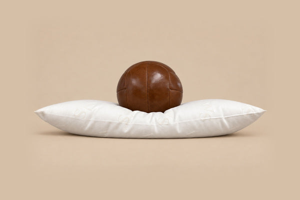 Thin wool pillow with a leather ball resting on it, sinking deep